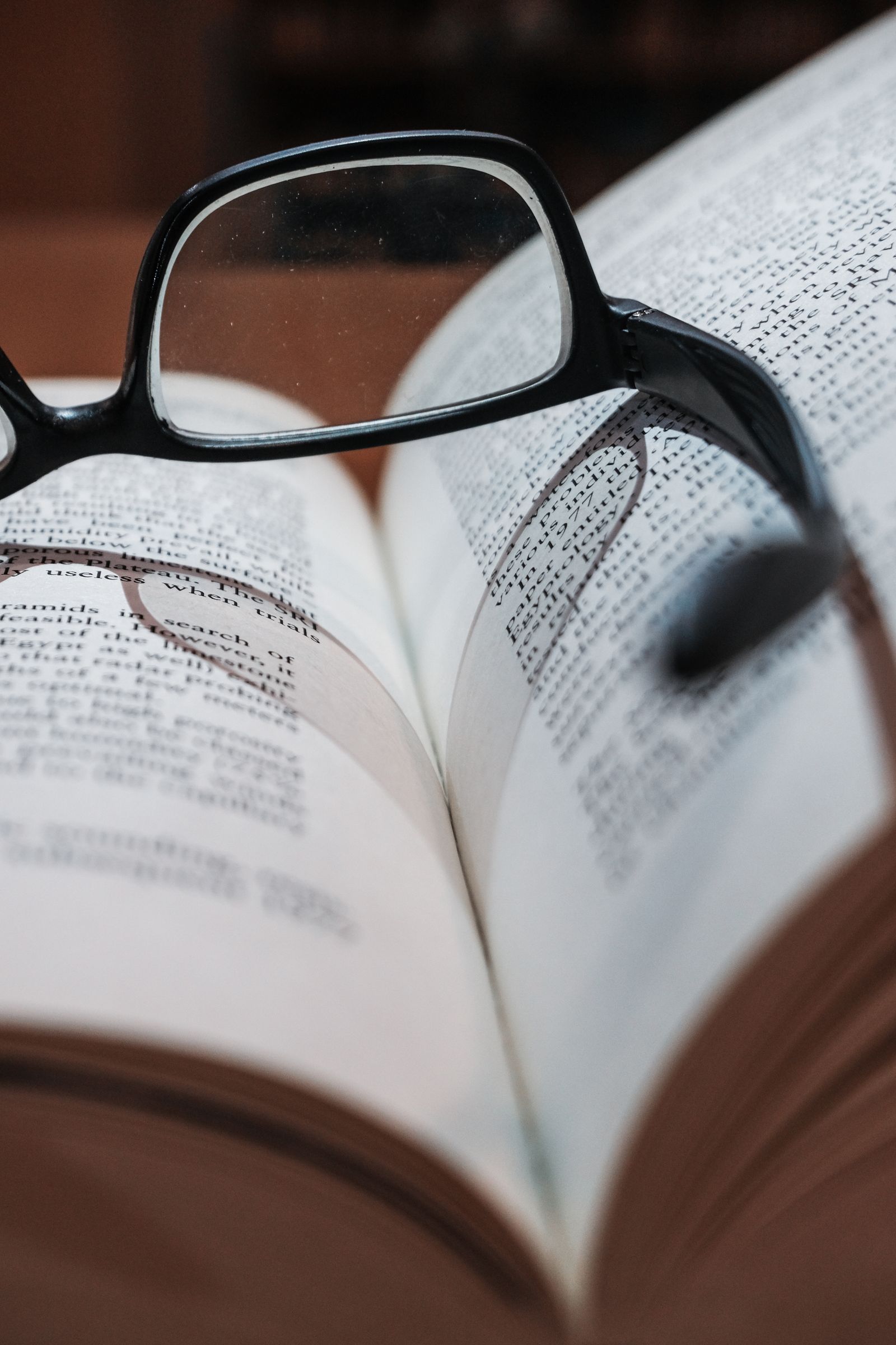 Occhiali appoggiati su un libro con testo nitido e sfocato a distanze diverse