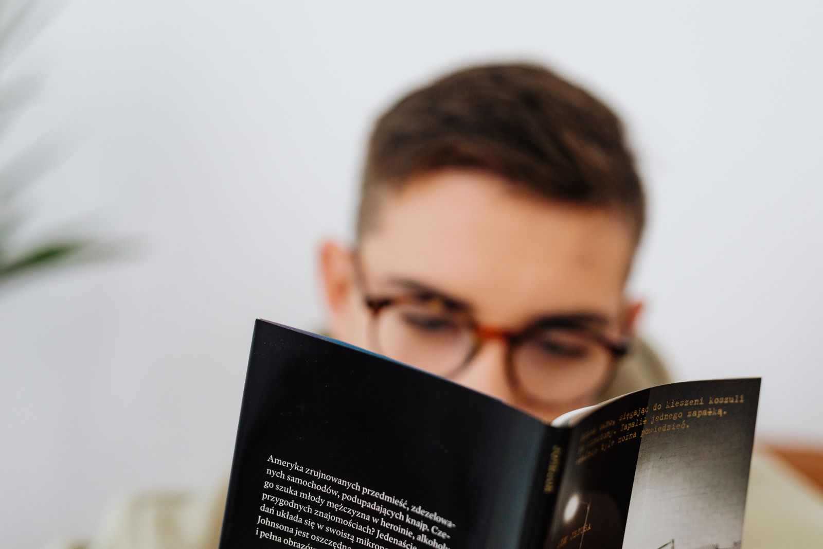 Uomo con occhiali mette a fuoco il testo di un libro vicino