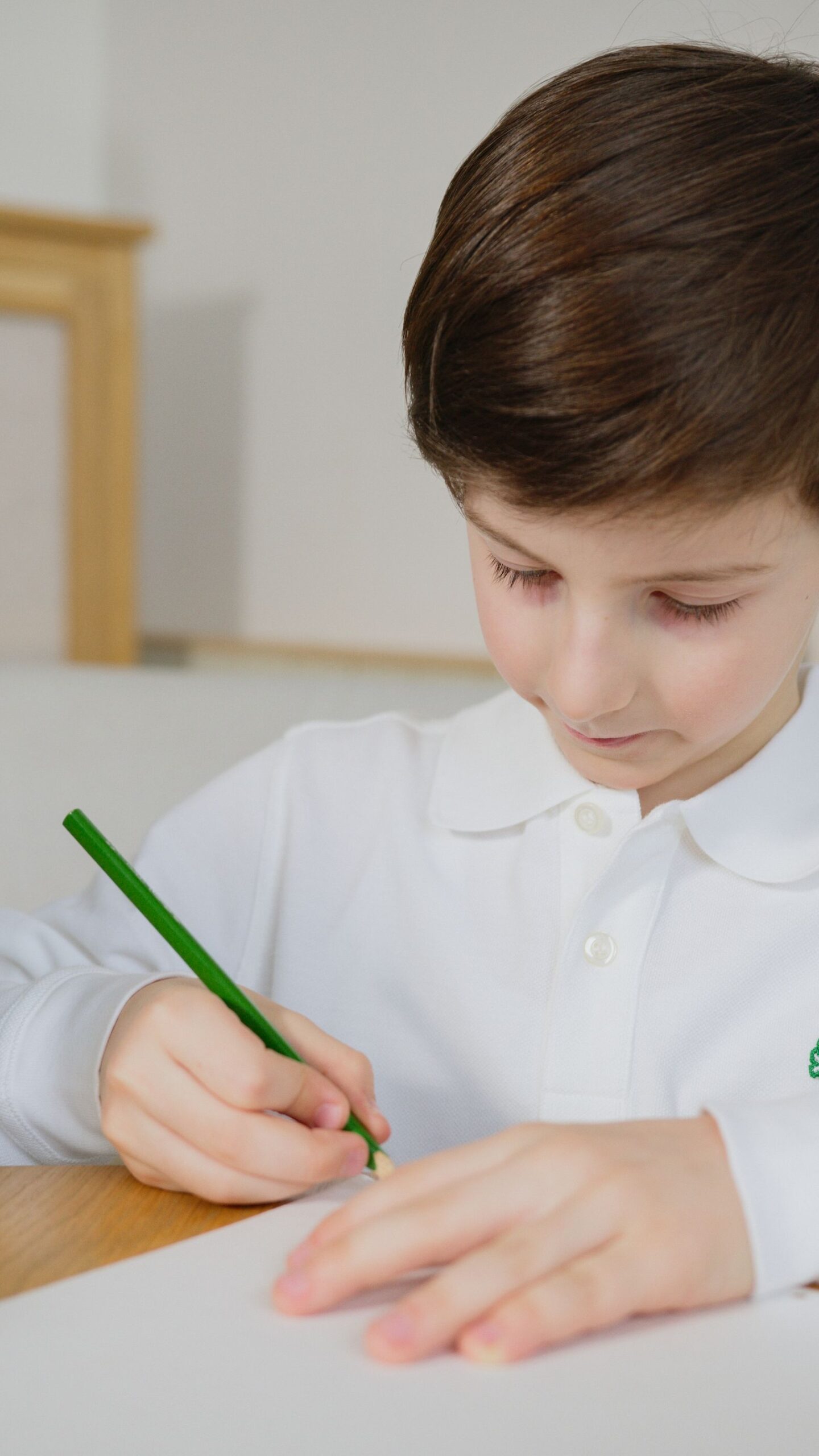 Bambino concentrato mentre scrive al tavolo