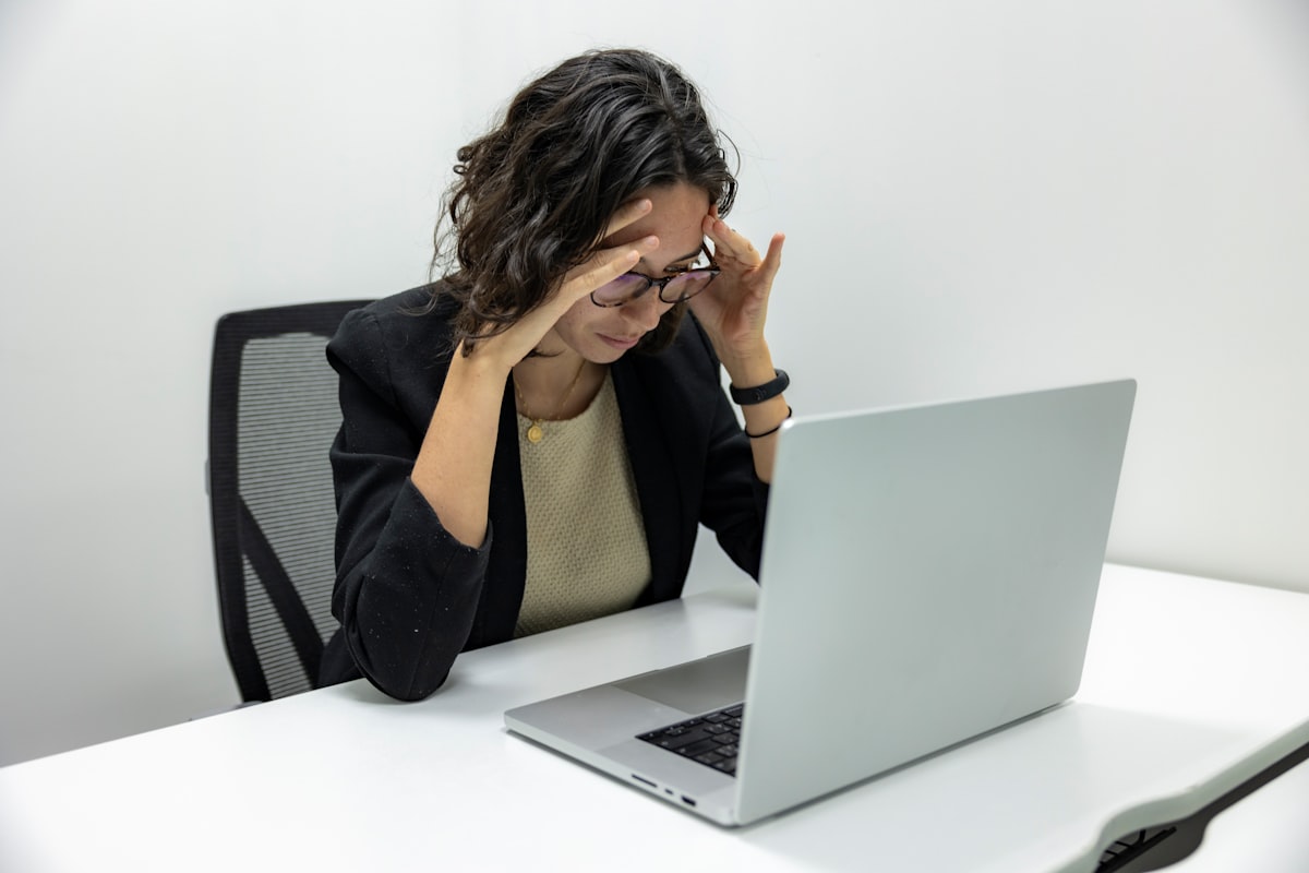 Donna con occhiali che si massaggia il collo davanti al computer in ufficio