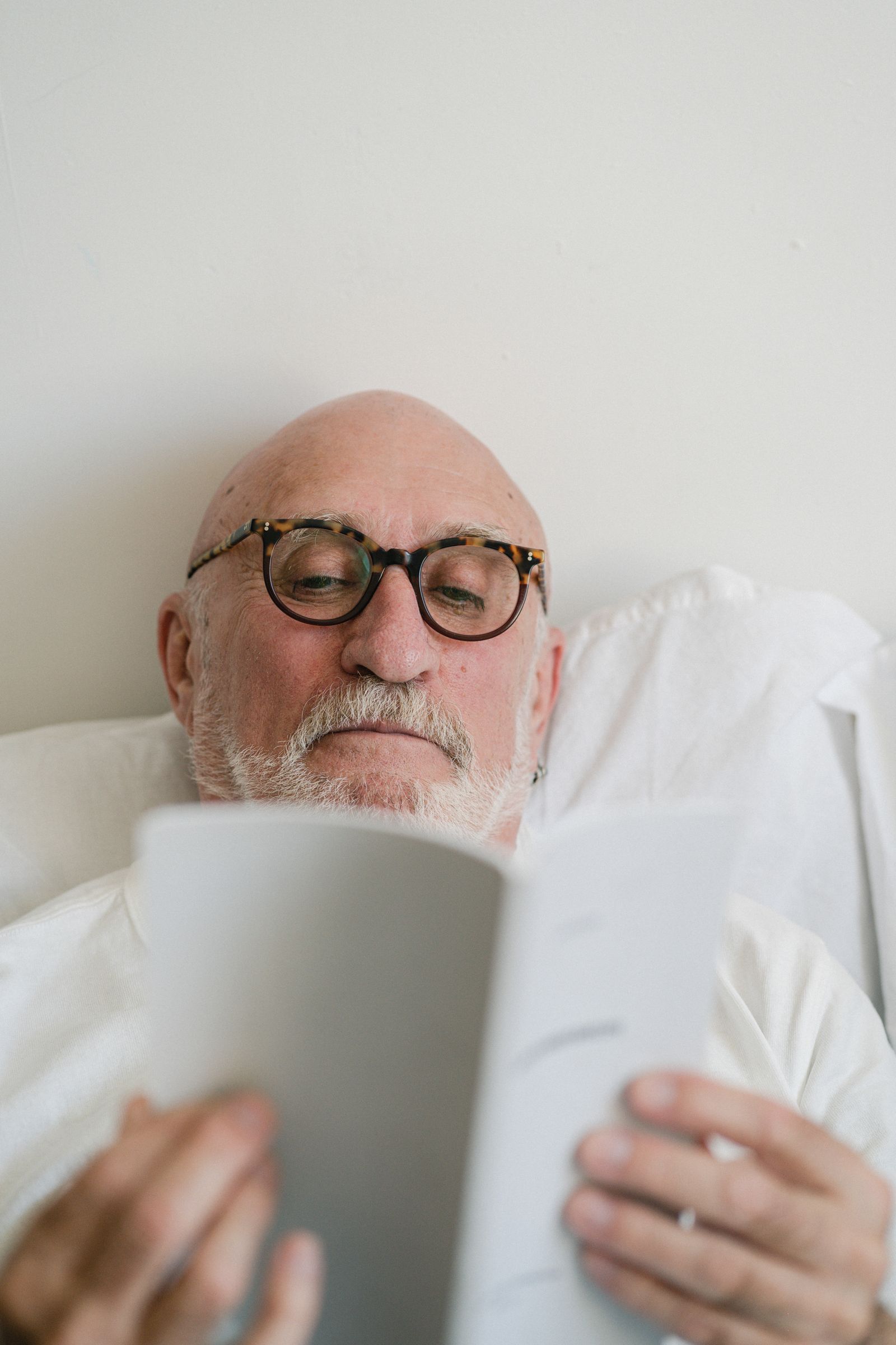 Uomo anziano con occhiali legge un documento durante la routine quotidiana