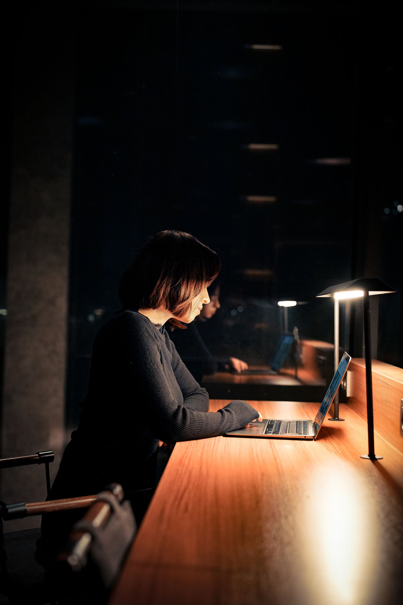 Donna che lavora al portatile di sera in un ambiente poco illuminato