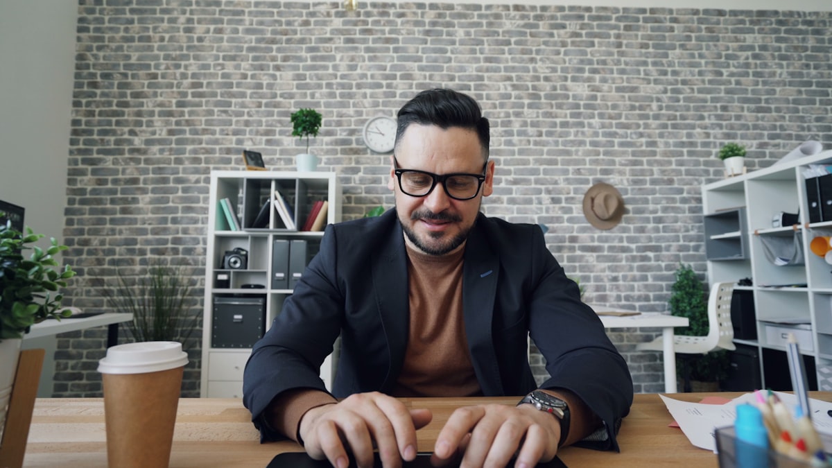 Uomo con occhiali concentrato e teso alla scrivania in ufficio