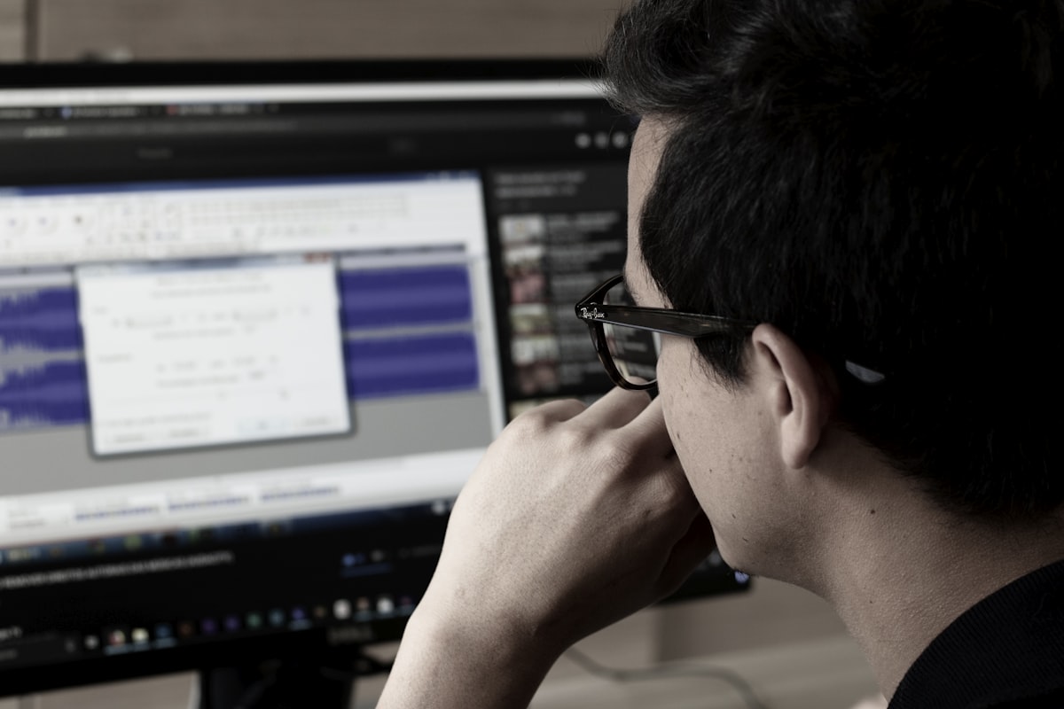 Uomo con occhiali concentrato davanti allo schermo del computer in ufficio