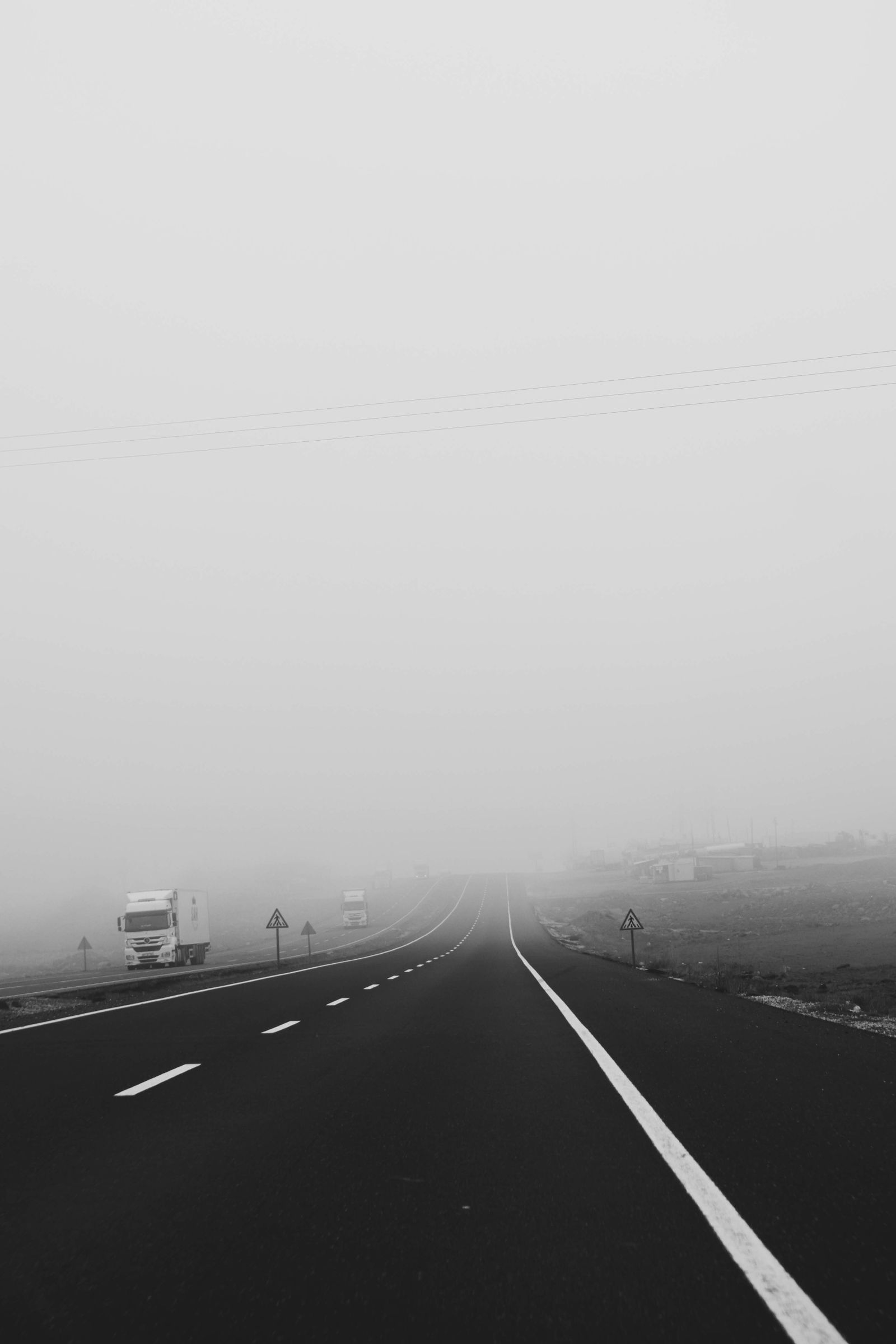Strada nella nebbia con segnaletica e veicoli a basso contrasto